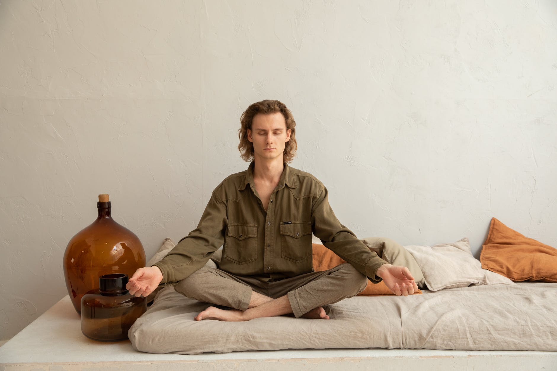serene man meditating in lotus pose on sofa
