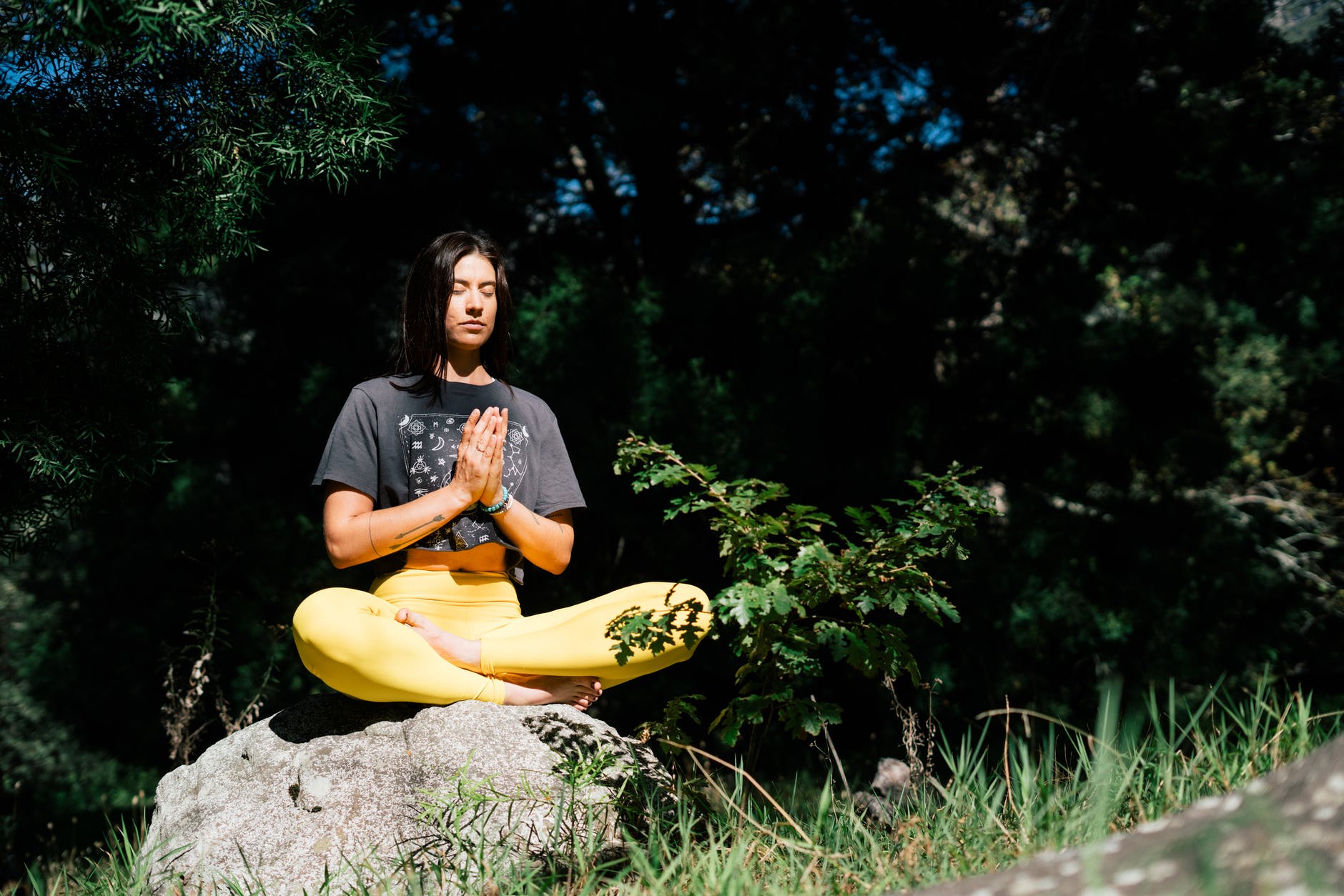 photo of woman doing yoga while sitting on rock